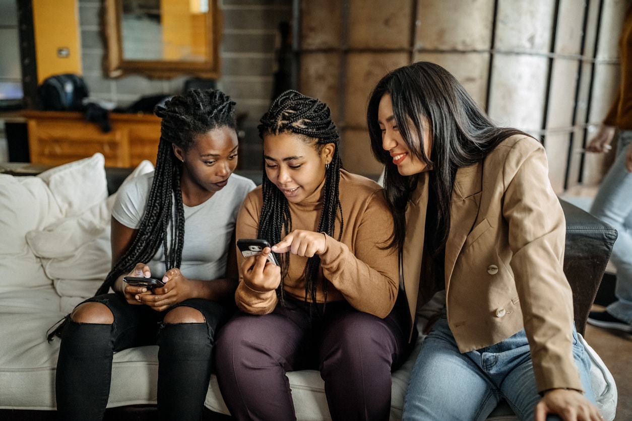 Group of diverse young women using their mobile phones to shop online, a concept of effective Gen Z marketing strategies.